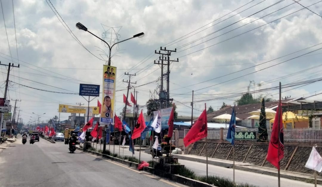 Bahan Kampanye dan Alat Peraga Kampanye, berdiri di median jalan dan sebagian diikatkan pada tiang lampu penerangan jalan umum di ruas Jalan Ahmad Yani dan SM Raja Sidikalang. Ketua Bawaslu Dairi menyebut penempatan APK tersebut melanggar ketentuan. (DETEKSI.co/Nainggolan)