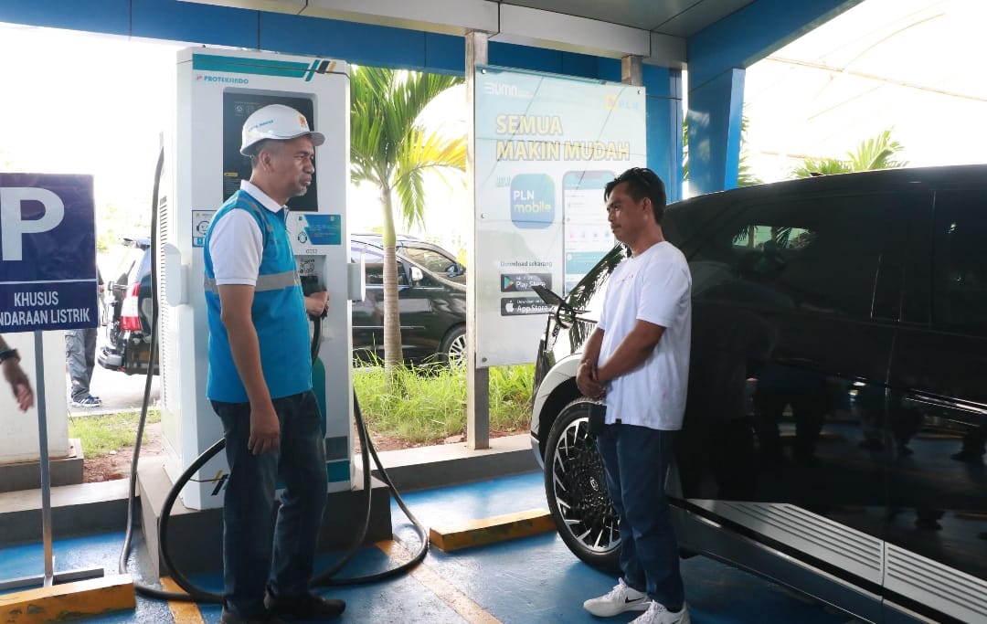 General Manager PLN Unit Induk Distribusi Banten Abdul Mukhlis (kiri) membantu salah seorang pemudik pengguna mobil listrik Andi Yani (kanan) saat melakukan pengisian daya di SPKLU rest area Pelabuhan Merak.