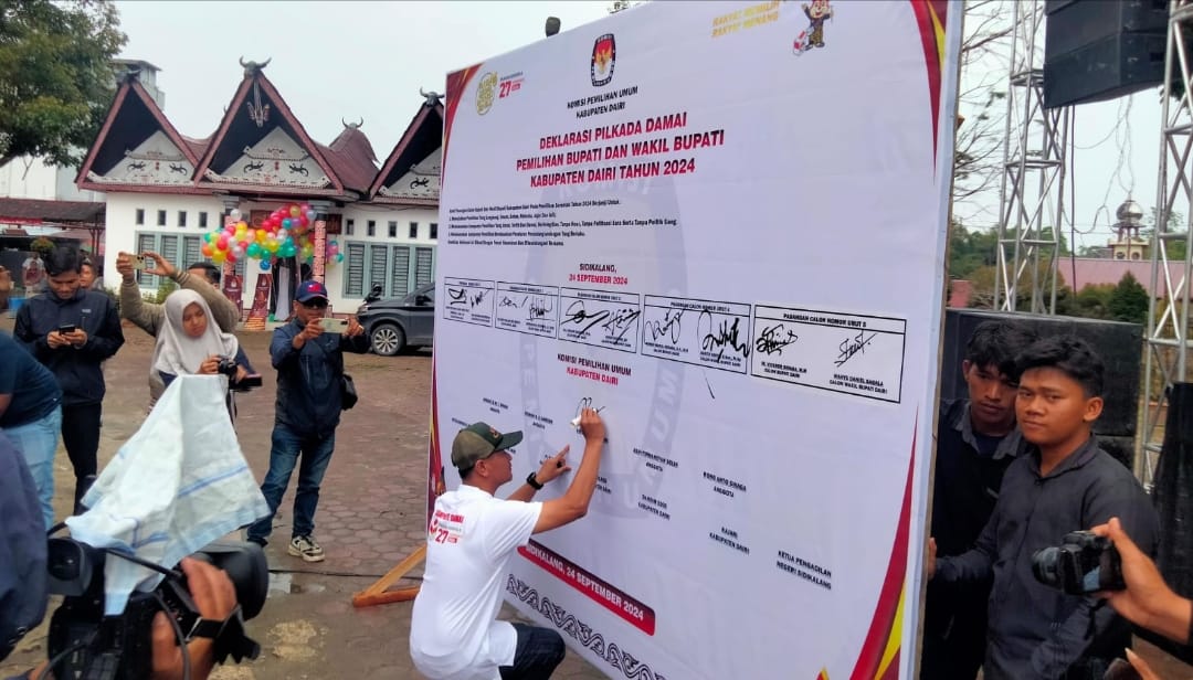 Ketua KPU Dairi membubuhkan tandatangan dalam naskah deklarasi kampanye damai Pilkada Dairi tahun 2024 di Gedung Nasional Djauli Manik, Selasa(24/9/2024) (DETEKSI.co/Parulian Nainggolan)