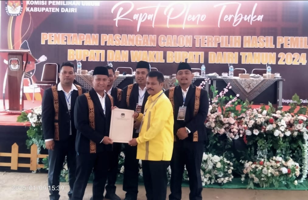 Ketua KPU Dairi, Ariyanto Tinendung didampingi komisioner menyerahkan dokumen penetapan Paslon Bupati-Wakil Bupati Dairi terpilih Hasil Pilkada 2024 kepada Sekretaris DPD Golkar Dairi, Pana Akbar Simatupang yang hadir mewakili Vickner Sinaga-Wahyu Daniel Sagala, Kamis (9/1/3025). (DETEKSI.co/Parulian Nainggolan)