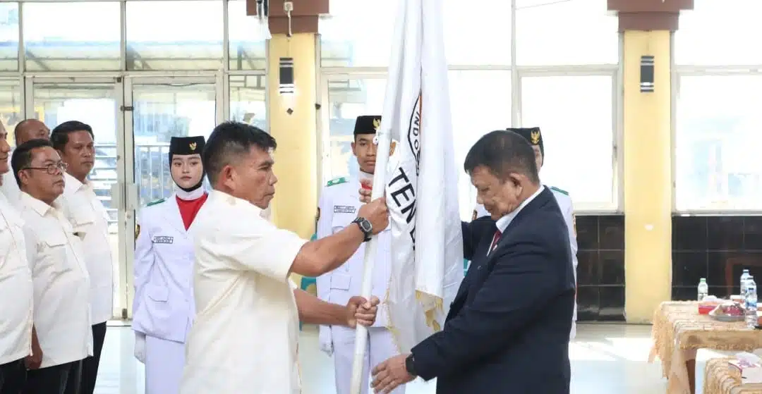Ketua Umum KONI Sumatera Utara Hatunggal Siregar menyerahkan Pataka kepada Ketua KONI Dairi Mangaranap Manik, pada seremoni pelantikan pengurus KONI Dairi, Selasa (24/6/2025) (DETEKSI.co/Parulian Nainggolan)