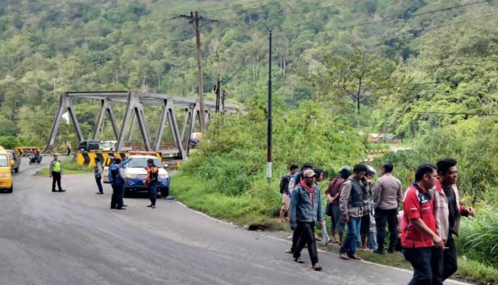 Personil Satlantas Polres Dairi bersama petugas dishub menormalisasi arus lalulintas disekitar lokasi kejadian yang sempat macet disebabkan banyaknya pengguna jalan yang berhenti untuk melihat mobil yang terjatuh dari bibir jurang. (DETEKSI.co/Parulian Phsp Nainggolan)