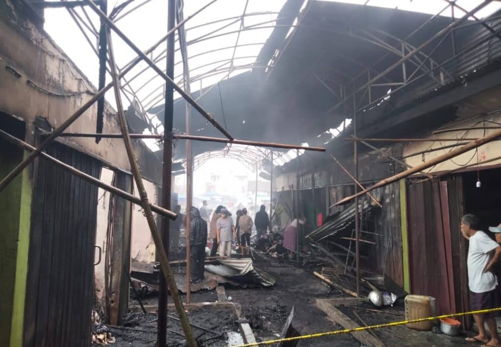 Pedagang melakukan pembersihan puing dan material sisa kebakaran.
