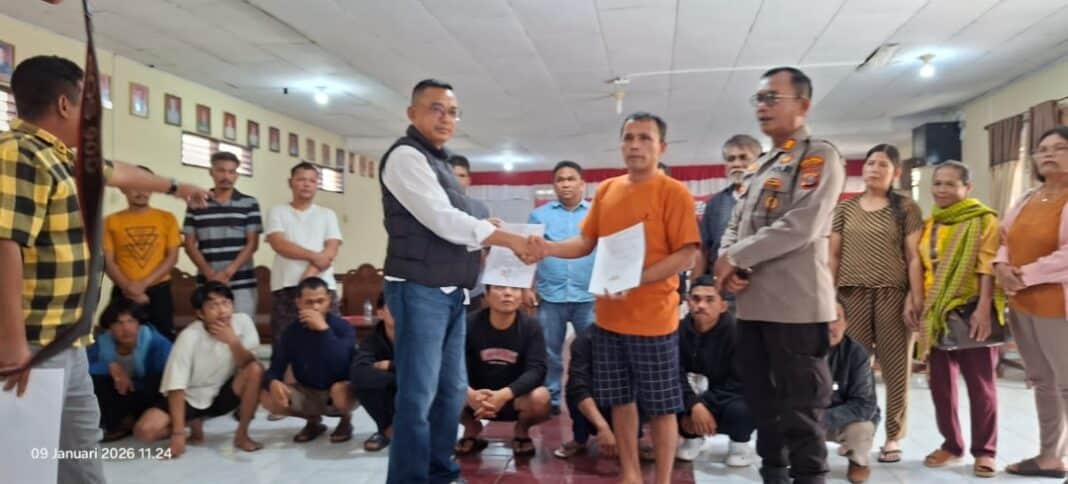 Pangihutan Sijabat (baju orange) bersalaman dengan Kery Sinaga, Penanggungjawab operasional PT Gruti, disaksikan para pihak dan tokoh masyarakat, menandai kesepakatan damai yang dilaksanakan di Aula Polres Dairi, Jumat (9/1/2026) (DETEKSI.co)
