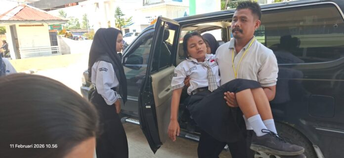 Guru SMK Arina Sidikalang menggendong salah seorang siswa ke Instalasi Gawat Darurat RSUD Sidikalang, untuk mendapat perawatan medis, Rabu (11/2/2026) (DETEKSI.co/Parulian Phsp Nainggolan)