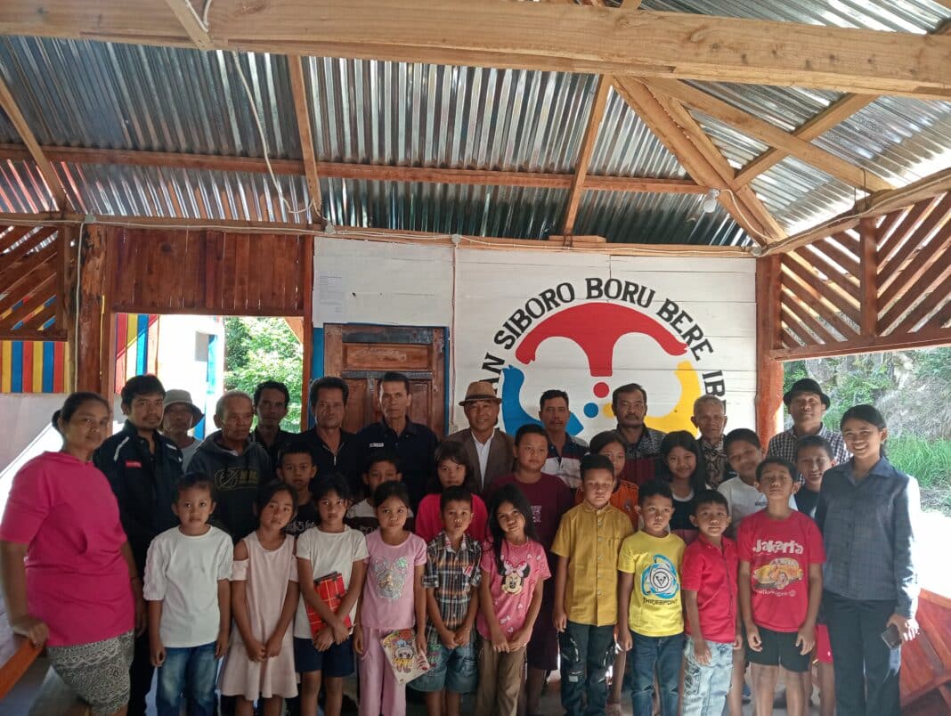 Ketua Umum PSBBI, Ombang Siboro bersama pengurus puguan lainya, guru les dari Lembaga Misi Bina Dunia, Tiara Sinaga, berpose bersama dengan anak anak yang ikut di group belajar Bina Anak di Partungkoran Sopo Belajar, Desa Siboro.(DETEKSI.co/hotdonnaibaho