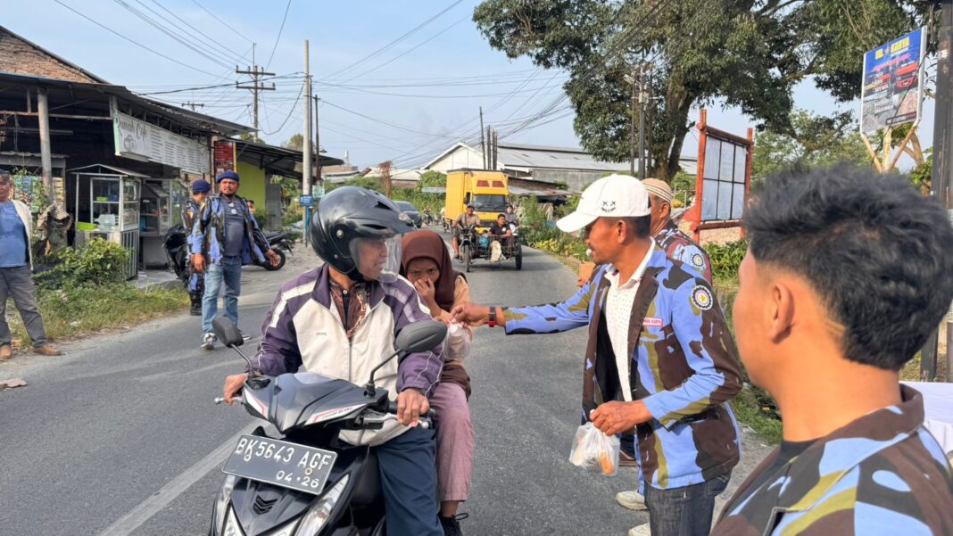 Ketua Satgas Inti DPD Ikatan Pemuda Karya (IPK) Sumatera Utara, Sartoto Barus, bersama kader membagikan paket takjil kepada pengendara dan masyarakat di depan Sekretariat Satgas Inti DPD Ikatan Pemuda Karya Sumut, Namo Rambe, Deli Serdang, Jumat (6/3/2026). Kegiatan bakti sosial tersebut merupakan bagian dari aksi berbagi Ramadhan dengan menyalurkan 1.000 paket takjil kepada warga yang melintas.