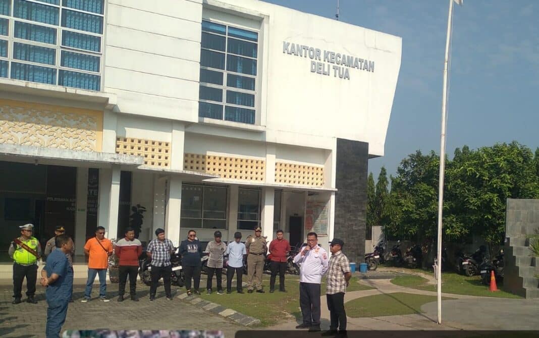Camat Delitua Rahmat Hidayat memimpin apel Jumat Bersih bersama ASN, Satpol PP, dan perangkat desa di halaman Kantor Camat Delitua, Jumat (24/04/2026), sebelum melakukan penertiban PKL dan parkir liar di jalan provinsi.