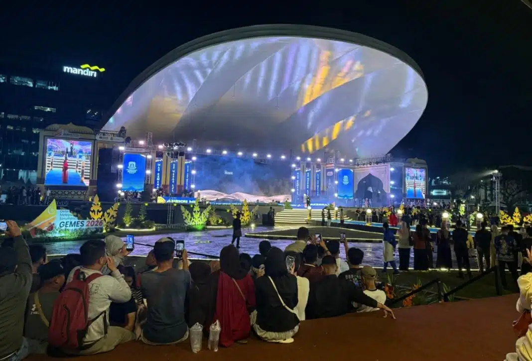 Sejumlah warga menyaksikan Gelar Melayu Serumpun (GEMES) XVIII/2026 dari luar pagar pembatas di Lapangan Merdeka Medan, Selasa (30/6/2026). Konsep area pertunjukan yang dibatasi pagar menuai kritik karena dinilai membuat masyarakat tidak dapat menikmati acara secara langsung.