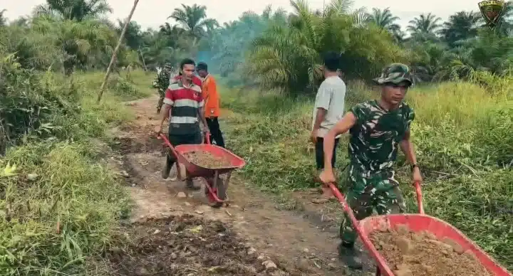Prajurit Yonif TP-905/TS bersama warga lokal melaksanakan kerja bakti dan gotong royong perbaikan ruas jalan.