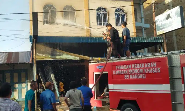 Petugas pemadam kebakaran bersama personel Polsek Bandar Huluan dan warga berupaya memadamkan api yang menghanguskan dua unit toko perabot dan elektronik di Jalan S.M. Raja, Kelurahan Perdagangan I, Kecamatan Bandar, Kabupaten Simalungun, Selasa (4/8/2026).