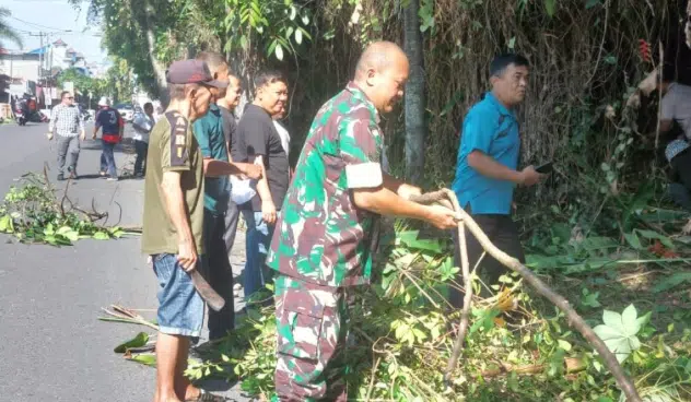 Personel Koramil 02/ST bersama pemerintah setempat dan warga bergotong royong membersihkan pohon serta semak belukar di bahu Jalan Sangnawaluh, Pematangsiantar, Jumat (21/8/2026). (Foto Dok. Pendam I/BB)