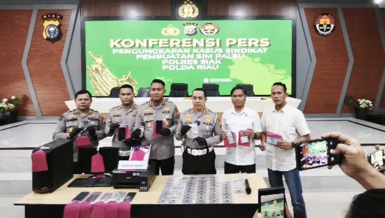 Dirlantas Polda Riau Kombes Pol Jeki Rahmat Mustika menyerahkan penghargaan kepada tiga pejabat Polres Siak atas pengungkapan jaringan pemalsuan SIM lintas wilayah Siak dan Pekanbaru di Gedung Media Center 91 Polda Riau, Kamis (17/9/2026). (Foto Dok. Humas Polda Riau)