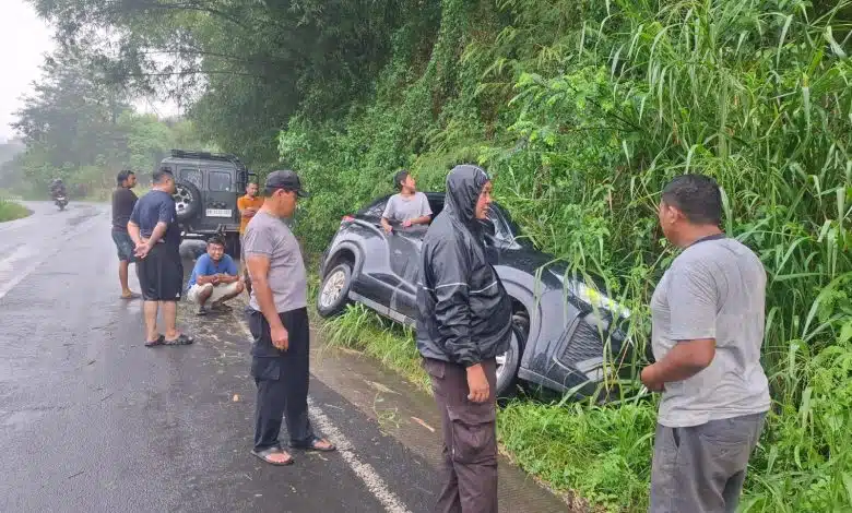 Personel Polsek Tigabinanga membantu evakuasi mobil Toyota Innova yang terperosok ke beram jalan di dekat Jembatan Lau Mandin, Kecamatan Tigabinanga, Kabupaten Karo, Rabu (14/10/2026). Kendaraan berhasil dievakuasi sekitar pukul 17.00 WIB melalui koordinasi dengan penyedia jasa mobil derek. (Foto Dok Bid. Humas Polda Sumut)